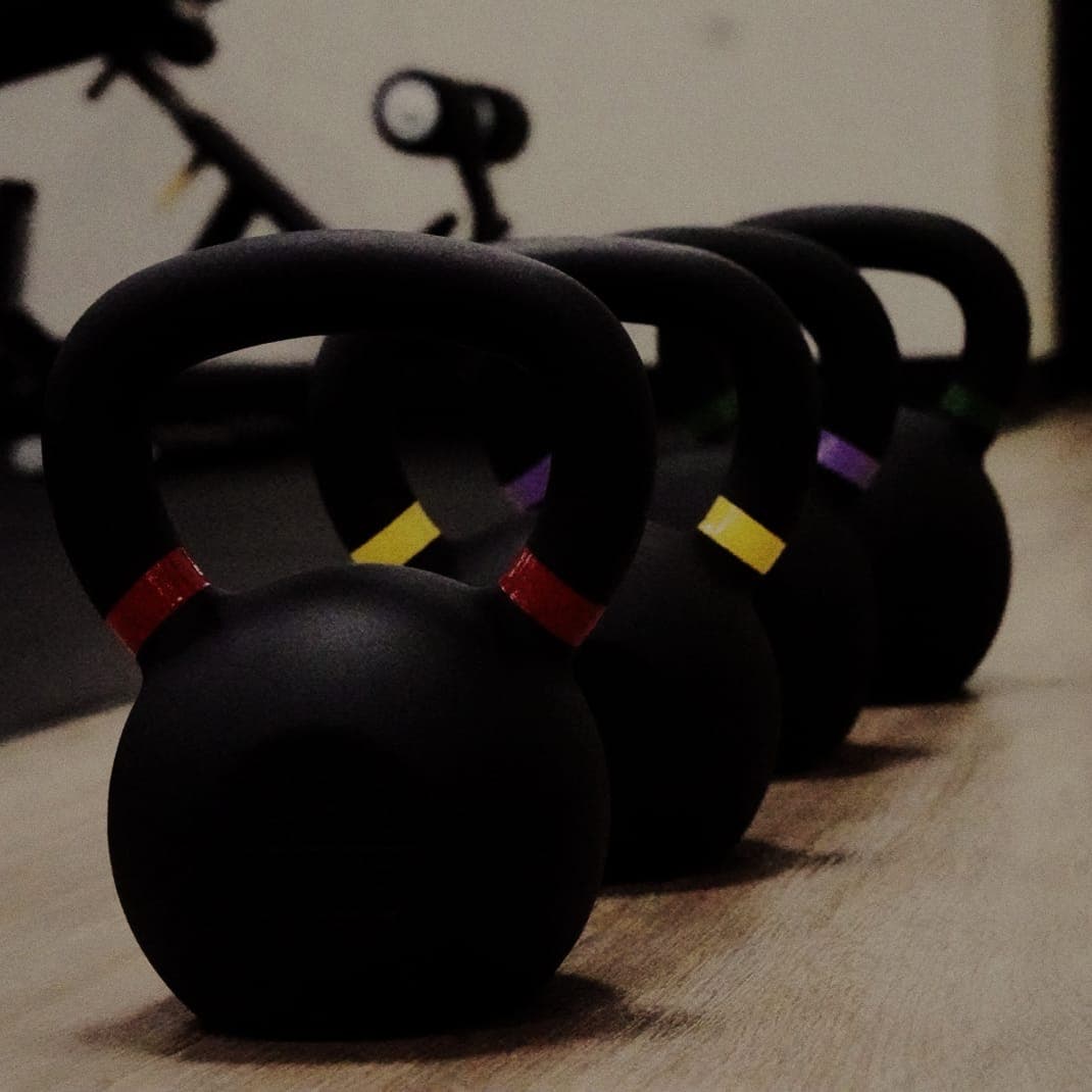 Color-coded kettlebells lined up on the floor at The Den